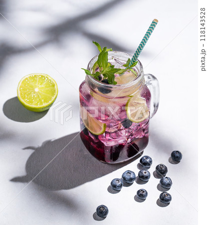 Blueberry mojito or lemonade with lime, ice and mint in a glass on a light background with berries 118143528