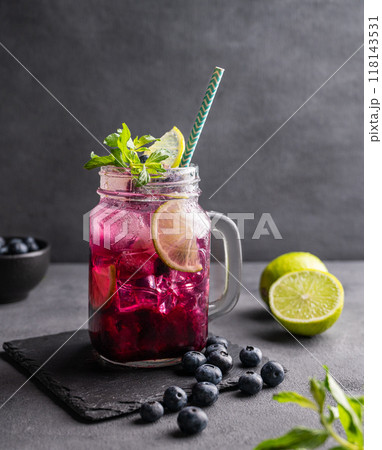 Refreshing blueberry mojito or lemonade with lime, mint and ice on a dark background. Refreshing blueberry mojito or lemonade with lime, mint and ice on a dark background. 118143531