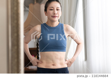 鏡の前で体型を気にするスポーツウェア姿の女性 鏡の前で体型を気にするスポーツウェア姿の女性 118144664