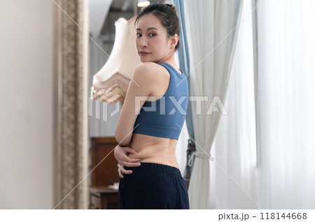 鏡の前で体型を気にするスポーツウェア姿の女性 鏡の前で体型を気にするスポーツウェア姿の女性 118144668
