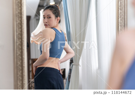 鏡の前で体型を気にするスポーツウェア姿の女性 118144672