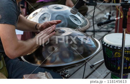 A musician skillfully plays the handpan at an outdoor event A musician skillfully plays the handpan at an outdoor event 118145613