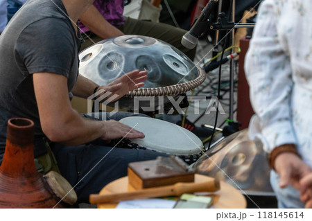 Musicians perform with handpan and tambourine at an outdoor gathering 118145614