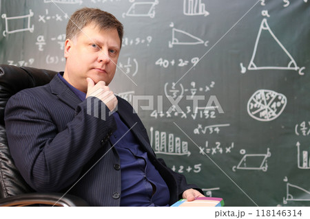 Portrait of a male teacher at a university sitting in a comfortable leather chair at the department 118146314