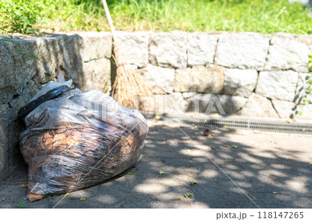 ビニール袋に入れられた落ち葉と竹ぼうき ビニール袋に入れられた落ち葉と竹ぼうき 118147265