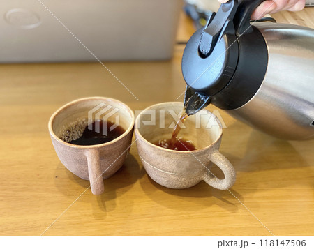 ノートパソコン前で2つのカップにコーヒーを注ぐ ノートパソコン前で2つのカップにコーヒーを注ぐ 118147506