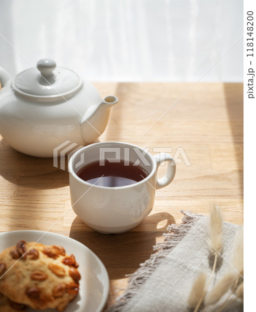 A cup of tea with homemade cookies and a white teapot on a wooden table against the background A cup of tea with homemade cookies and a white teapot on a wooden table against the background 118148200