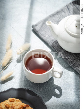 A cup of fragrant tea with homemade cookies and a white teapot on a blue background A cup of fragrant tea with homemade cookies and a white teapot on a blue background 118148207