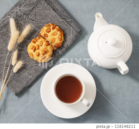 A cup of fragrant tea with homemade cookies and a white teapot on a blue background. A cup of fragrant tea with homemade cookies and a white teapot on a blue background. 118148211