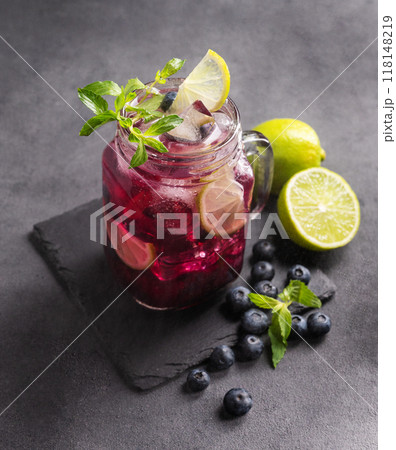 Refreshing blueberry mojito or lemonade with lime, mint and ice on a dark background. Refreshing blueberry mojito or lemonade with lime, mint and ice on a dark background. 118148219