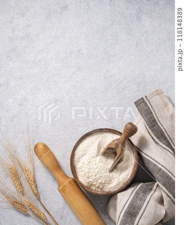 Natural flour in a wooden bowl with a scoop, rolling pin and napkin on a blue background Natural flour in a wooden bowl with a scoop, rolling pin and napkin on a blue background 118148389