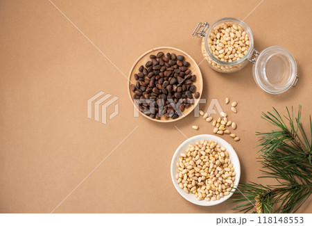 Pine nuts in a bowl and jar on a yellow background with branches of pine needles.  118148553