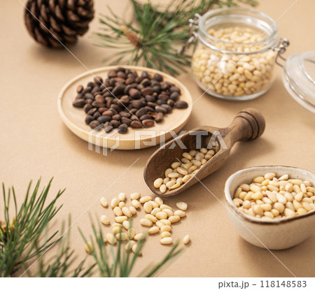 Pine nuts  in a jar and wooden scoop  on a yellow background with branches of pine needles  118148583