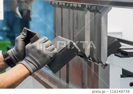 Close up the press brake bending machine operator hold the sheet metal parts with safety glove. 118148739
