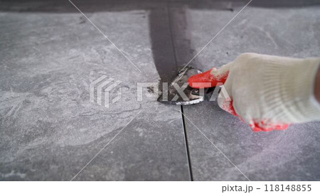 Construction worker applying grout to tile floor 118148855