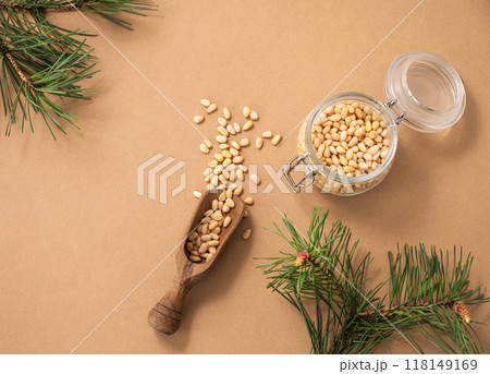 Pine nuts in jar and scoop on a yellow background with branches of pine needles. Pine nuts in jar and scoop on a yellow background with branches of pine needles. 118149169