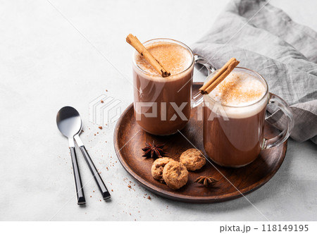 Two glass mugs with hot chocolate and milk foam on a wooden board on a gray background Two glass mugs with hot chocolate and milk foam on a wooden board on a gray background 118149195