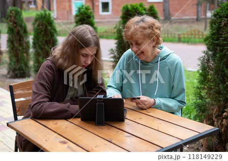 A teenage girl and an older woman spend time together. A teenage girl and an older woman spend time together. 118149229