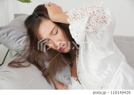 A woman in a white nightgown appears to be experiencing dizziness at night. 118149426