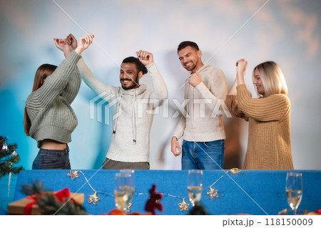 A group of very positive friends are having fun at a party. A group of friends are dancing in the background at Christmas. Happy guys and girls celebrate the New Year in a homely atmosphere. Super 118150009