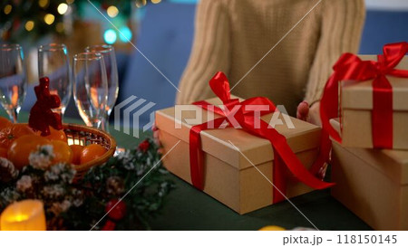 Christmas Red and White Gift and Ornaments Background. Christmas gift on the table against the background of the Christmas tree. Christmas handmade gift box on the background of a decorated Christmas 118150145
