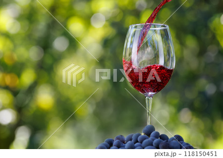 red wine pouring into glass with green background 118150451