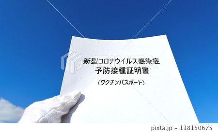 ワクチン接種証明書文字入り用紙を持つ白手袋の手_青空背景 ワクチン接種証明書文字入り用紙を持つ白手袋の手_青空背景 118150675