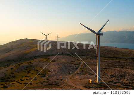 Wind turbines generate eco-friendly power on Pag Island, encircled by the Adriatic Sea at sunset.  118152595