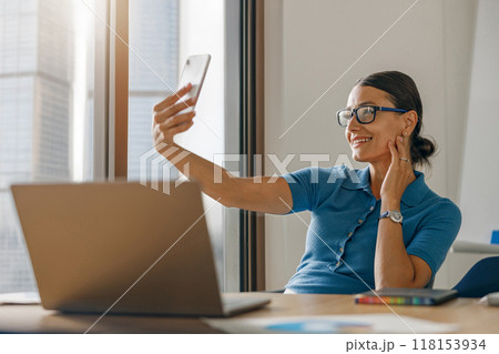 A woman is engaged in a lively video call while she is working from the comfort of her home A woman is engaged in a lively video call while she is working from the comfort of her home 118153934