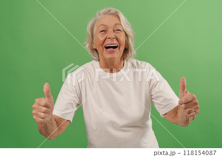 A Happy Elderly Woman Gives a Thumbs Up Gesture to Show Her Approval and Joyfulness A Happy Elderly Woman Gives a Thumbs Up Gesture to Show Her Approval and Joyfulness 118154087