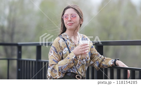 Pensive happy woman sipping a milkshake in the street 118154285