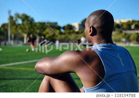 Rear view athletic man sitting on grassy sports football field 118154788