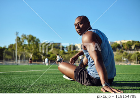 Athletic man sitting on grassy sports football field look at camera 118154789