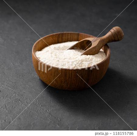 Wheat or oat flour in a wooden bowl with scoop on a dark background. Organic baking ingredients. Concept of homemade and healthy food. Wheat or oat flour in a wooden bowl with scoop on a dark background. Organic baking ingredients. Concept of homemade and healthy food. 118155786
