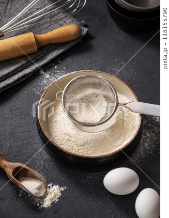 Flour, eggs and rolling pin on a dark background close up. Organic baking ingredients. Flour, eggs and rolling pin on a dark background close up. Organic baking ingredients. 118155790