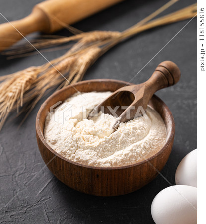 Organic baking ingredients. Wheat flour, eggs and rolling pin on a dark  background close up. 118155816