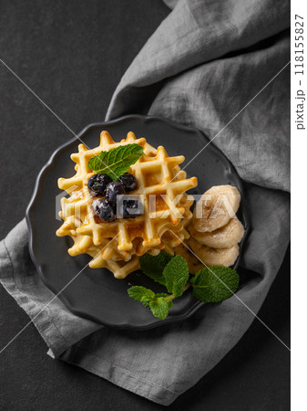 A stack of belgian waffles with kiwi, banana slices and mint, drizzled with honey syrup A stack of belgian waffles with kiwi, banana slices and mint, drizzled with honey syrup 118155827