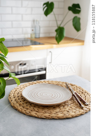 Wooden blue table top with flower pot and plate for breakfast against blurred white kitchen Wooden blue table top with flower pot and plate for breakfast against blurred white kitchen 118155887