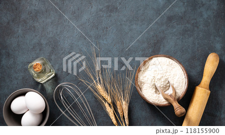 Flat lay organic baking ingredients. Wheat flour, eggs, oil, rolling pin on a dark  background.  118155900