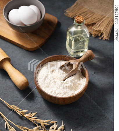 Oatmeal in a wooden bowl with eggs, rolling pin and oil on a dark background.  118155904