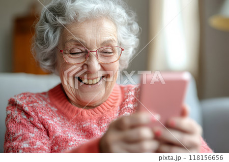 Elderly woman smiles while using a smartphone 118156656
