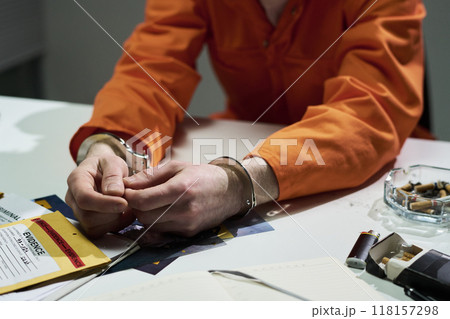 Handcuffed Person Wearing Orange Uniform Sitting at Desk Handcuffed Person Wearing Orange Uniform Sitting at Desk 118157298