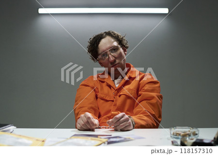 Sitting Man in Orange Jumpsuit Holding Handcuffs 118157310