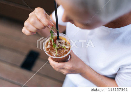 Closeup top view of unrecognizable woman holding cup of iced coffee with straw in urban setting on summer day. Cup of cold bubble tea with straw in female hand. Concept of drink, lifestyle, city life Closeup top view of unrecognizable woman holding cup of iced coffee with straw in urban setting on summer day. Cup of cold bubble tea with straw in female hand. Concept of drink, lifestyle, city life 118157561