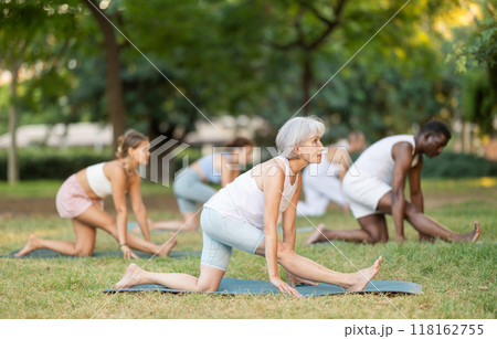 Yoga for people of different ages - elderly woman practicing different yoga poses together in park 118162755