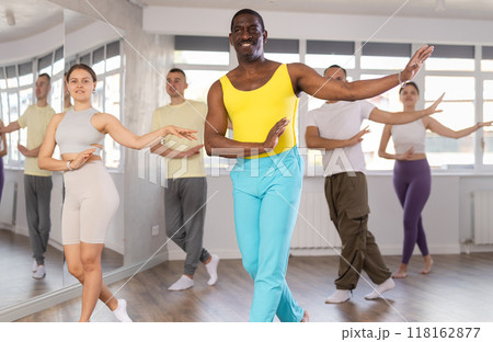 Positive black man participating in group Latin dance class Positive black man participating in group Latin dance class 118162877