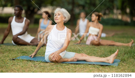 Yoga for people of different ages - elderly woman practicing different yoga poses together in park 118162894