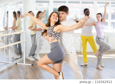 Happy pretty woman enjoying impassioned merengue with male partner in dance room during class. Social dancing concept Happy pretty woman enjoying impassioned merengue with male partner in dance room during class. Social dancing concept 118162912