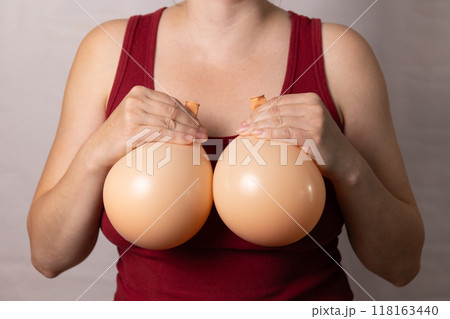 A woman holds balloons demonstrating the concept of breast modification after plastic surgery 118163440