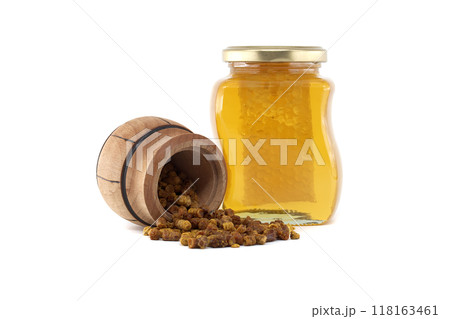 Natural bee bread spilling from a wooden barrel isolated on white background 118163461